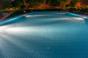 Closeup shot of a swimming pool in the park at dark night - obrazy, fototapety, plakaty