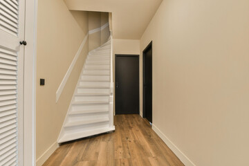 an empty room with wooden floors and white shutters on the walls, there is a staircase leading up...