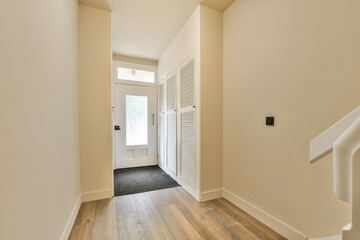 an empty room with wood flooring and white shutters on the wall behind it is a door that leads to...