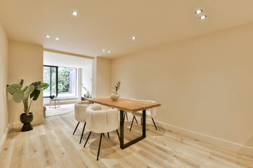 a living room with white walls and hardwood flooring, including a wooden dining table surrounded by two stools