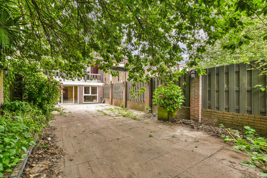 an outside area with trees and plants on the ground next to a brick building that has been built for sale