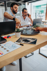 Young, handsome, male employee pouring water in glasses for his coworkers while working together at the office.