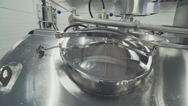 Close-up of a stainless steel tank used for milk processing at the factory. Stainless steel tank with huge amounts of dairy product inside. Stainless steel tank for milk pasteurization at dairy plant.