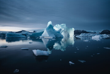 a landscape of icebergs at night with moon and stars