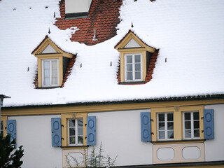Mit Schnee bedeckte Dachgauben mit Fenstern auf einem barocken Schlossdach