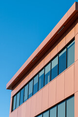 Obraz premium The exterior wall of a contemporary commercial style building with aluminum metal composite panels and glass windows. The futuristic building has engineered diagonal cladding steel frame panels.