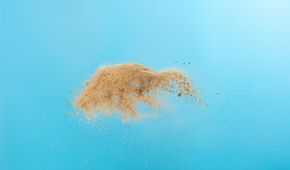 Big size Sand flying scatter, Golden grain wave explode. Abstract cloud fly. Yellow colored sand splash throwing in Air. Blue sky background Isolated, throwing freeze stop motion