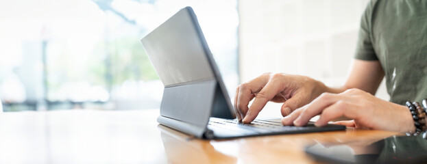 Closeup man hand using digitaltablet, typing on magic keyboard, copy space.