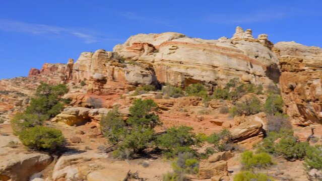Establishing shot of mountain trail with red rocks background in Hickman Natural Bridge Trail, Capital Reef National Park, Utah, North America. Day time on October 2023. Still camera view. ProRes 422 