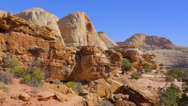 Establishing shot of mountain trail with red rocks background in Hickman Natural Bridge Trail, Capital Reef National Park, Utah, North America. Day time on October 2023. Still camera view. ProRes 422 