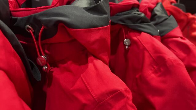 Red sports membrane jackets with a hood for hiking hang on the rack in a sportswear store