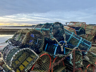 St Andrews, Scotland - September 22, 2023: Lobster traps and pots on the docks of the marina in St Andrews Scotland at sunrise
