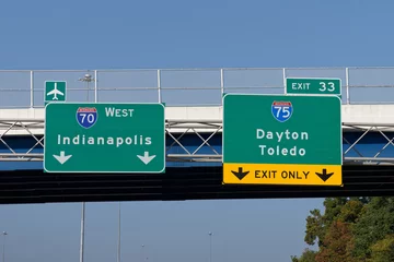 Fotobehang Signs on Interstate 70 for continuing west toward Indianapolis and the Dayton International Airport and exit 33 for Interstate 75 toward Dayton and Toledo, Ohio © Rosemarie Mosteller