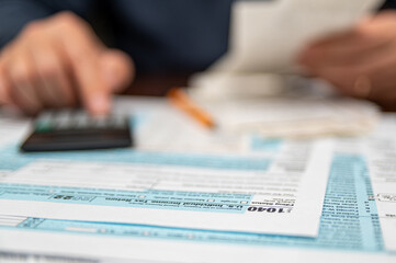 A man organizing individual income tax return form 1040 and receipts. Blurred background. Tax time.Tax concept. Close-up. - obrazy, fototapety, plakaty