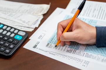 A man organizing individual income tax return form 1040 and receipts. Blurred background. Tax time.Tax concept. Close-up.
