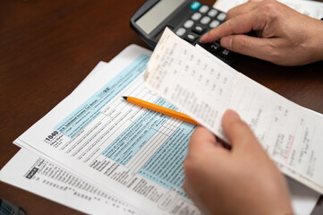 Fototapeta premium A man organizing individual income tax return form 1040 and receipts. Blurred background. Tax time.Tax concept. Close-up.