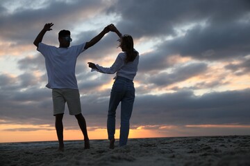 Fototapeta premium Happy couple dancing on beach at sunset