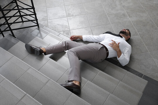 Unconscious man lying on floor after falling down stairs indoors