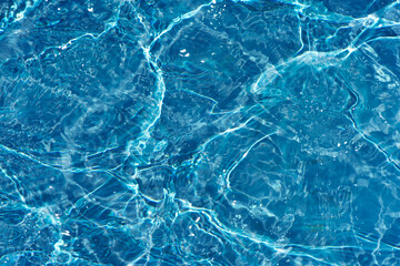 Fototapeta na wymiar Defocus blurred transparent blue colored clear calm water surface texture with splashes reflection. Trendy abstract nature background. Water waves in sunlight with copy space. Blue watercolor shine.