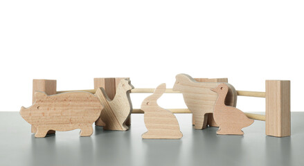 Set of wooden animals and fence on light grey table against white background. Children's toy