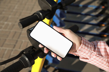 Woman using smartphone to pay and unblock electric kick scooter outdoors, closeup