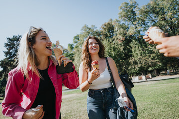 Caucasian friends spend a carefree day off in a city park, enjoying nature, talking, and eating ice cream. They feel free and happy creating positive energy.