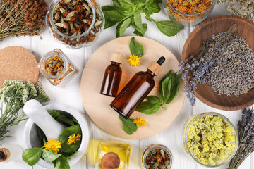 Bottles of essential oils surrounded by different herbs on white wooden table, flat lay