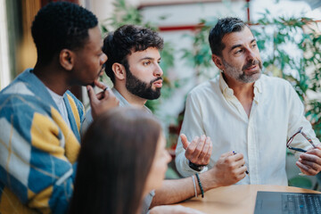 Multiracial team analyzing projects, discussing ideas, and collaborating for better efficiency and growth. Experienced business leaders sharing knowledge in a successful corporate setting.