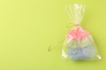 Packaged sweet cotton candy on green background, top view. Space for text