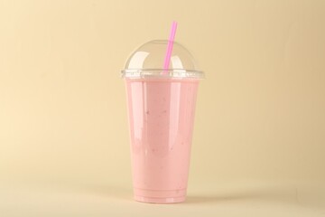 Plastic cup of tasty smoothie on beige background - obrazy, fototapety, plakaty