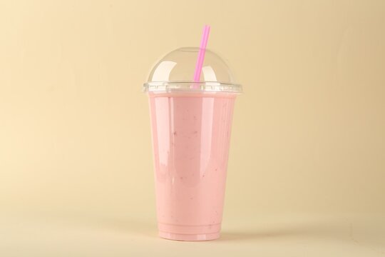 Plastic cup of tasty smoothie on beige background