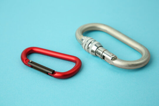 Two metal carabiners on light blue background, closeup