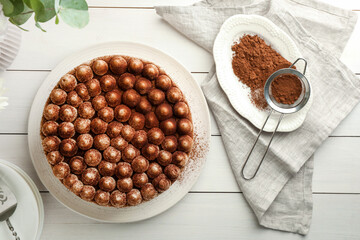Delicious tiramisu cake with cocoa powder on white wooden table, flat lay