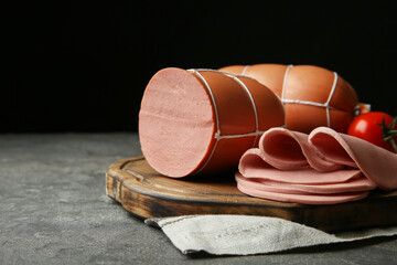 Board with tasty boiled sausages on dark textured table against black background, closeup. Space for text