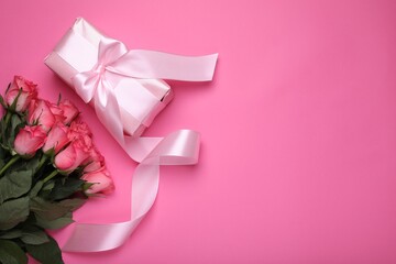 Beautiful gift box with bow and roses on pink background, flat lay. Space for text