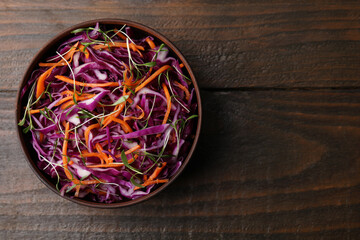 Tasty salad with red cabbage in bowl on wooden table, top view. Space for text