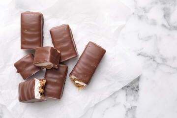 Tasty chocolate bars with nougat on white marble table, top view. Space for text
