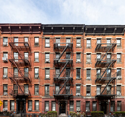 Block of classic old brick apartment buildings with windows and fire escapes in New York City - obrazy, fototapety, plakaty