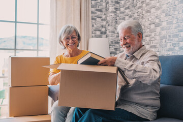 Relaxed mature married couple in love resting on couch among paper cardboard boxes, taking break,...