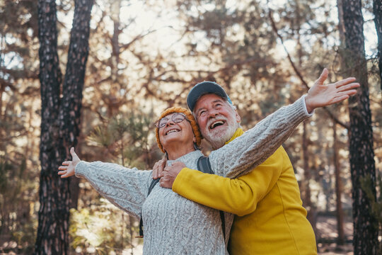 Head shot portrait close up of one old mature couple looking at the trees enjoying nature alone in the forest.Pensioner people with opened arms feeling free, freedom concept..