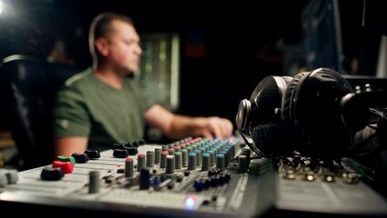 A close-up of a mixing console device used by a man working as professional sound engineer in a music studio