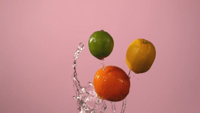 Citrus Fruit Falling In Slow Motion Against Pink Background