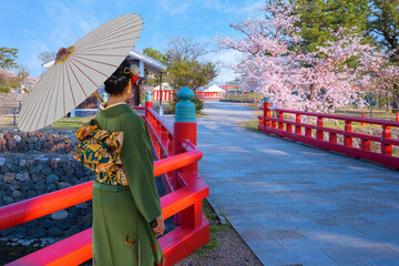 Young Japanese woman in a traditional Kimono dress strolls in Prefectural Uji Park in Kyoto, Japan...