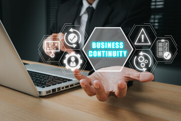 Business continuity concept, Businessman working on laptop computer and hand holding business continuity icon on virtual screen.