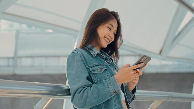 Young asian woman standing in the city, using mobile smartphone on the street
