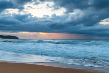Sunrise seascape with low clouds and waves