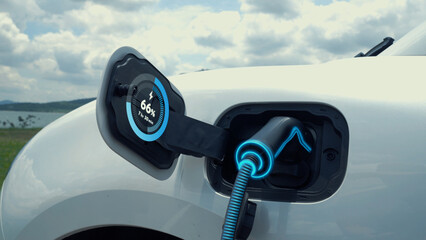 Electric car plug in with charging station, recharge battery by EV charger cable display smart digital battery status hologram with nature background. Futuristic green energy infrastructure.Peruse