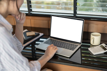 Back view of a businesswoman working on her laptop indoors, thinking and planning her work.
