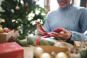 Woman preparing christmas gift box at home.