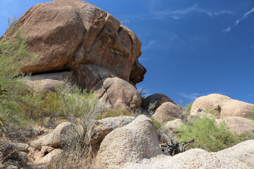 The massive boulders looming on the edge of a hillside display a range of colors, including earthy tones such as browns, reds, and grays, reflecting the minerals present in the rock. 